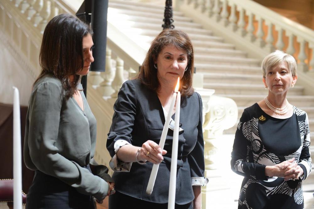 At 2013 Days of Remembrance ceremony, Susan Segall lights a candle in honor of her father, World War II Liberator Laurence Grossman. 